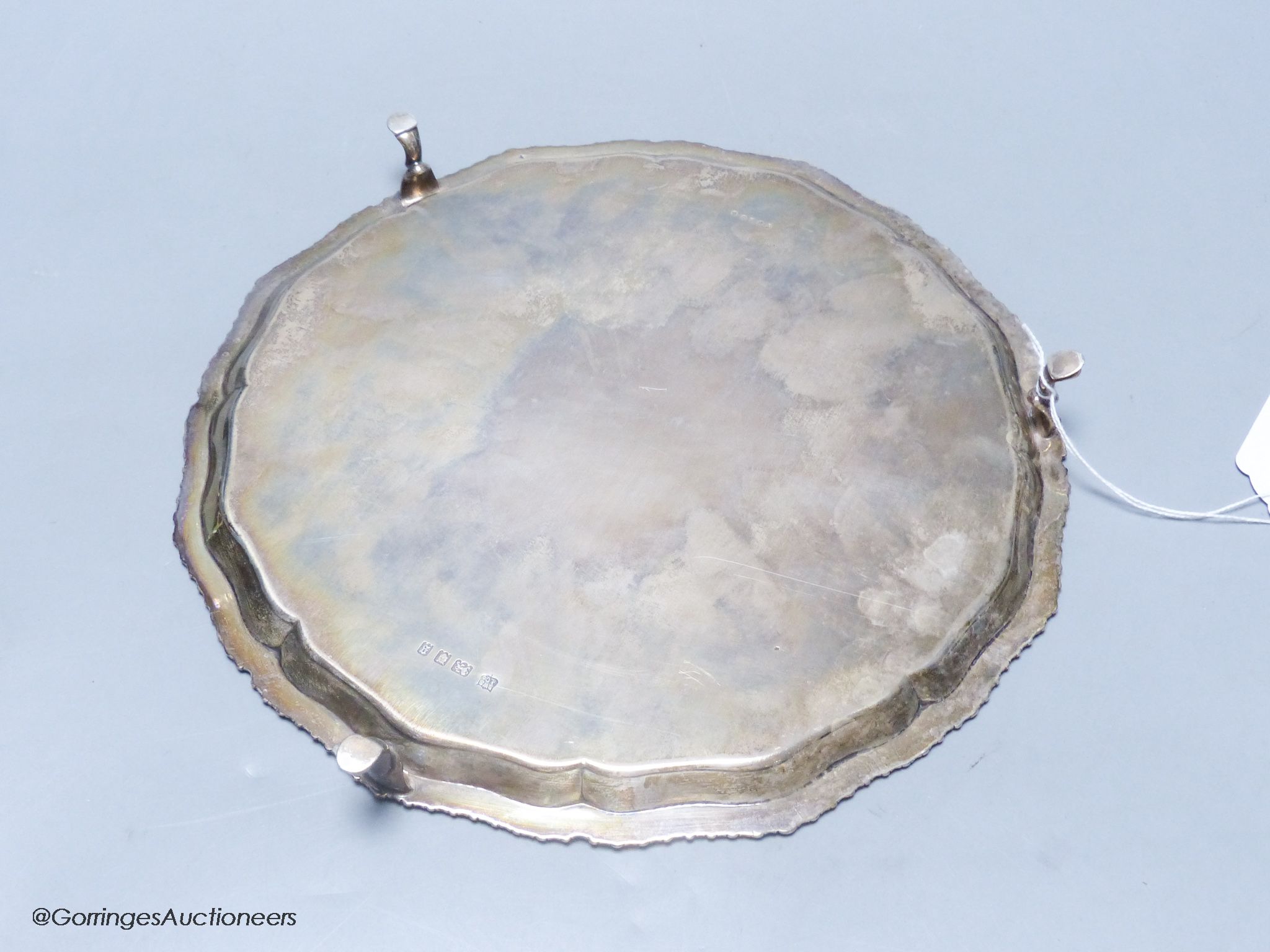 A circular silver salver with shaped gadrooned edge, on three hoof feet, 14.79oz